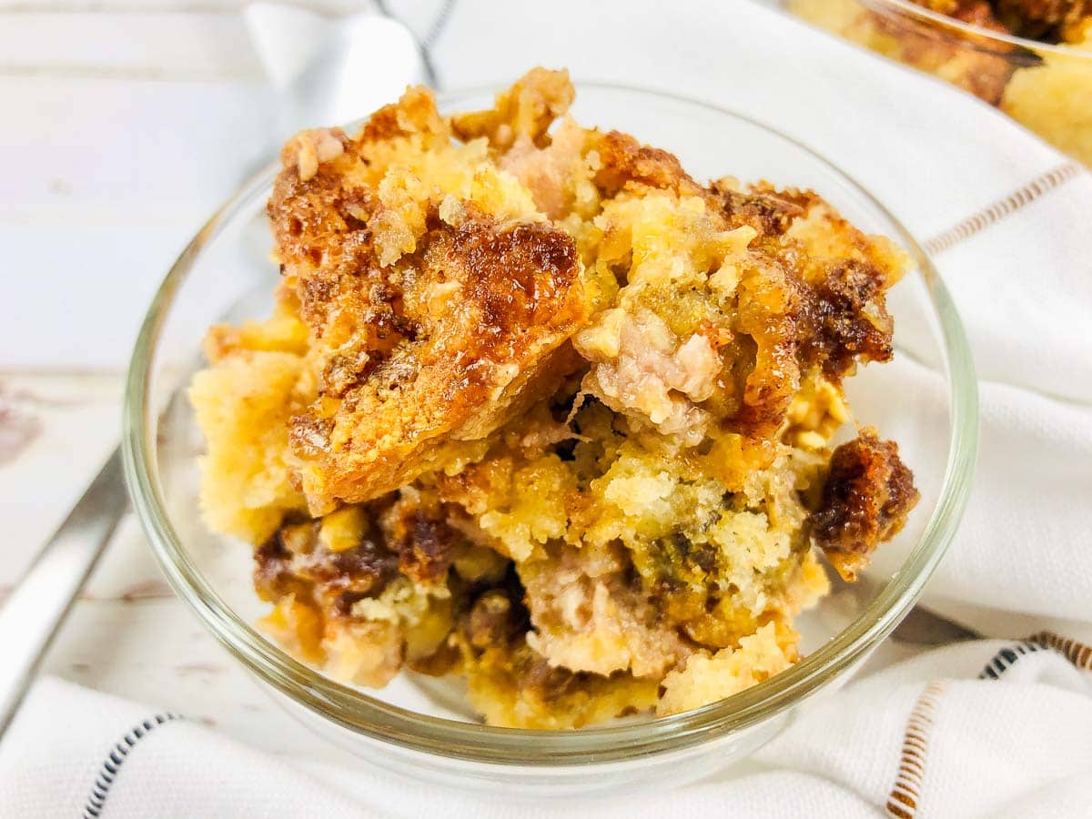 A scoop of banana bread dump cake in a glass bowl, with a crispy top and soft, moist inside.