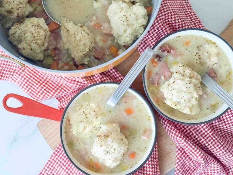 A group of bowls of soup with spoons.