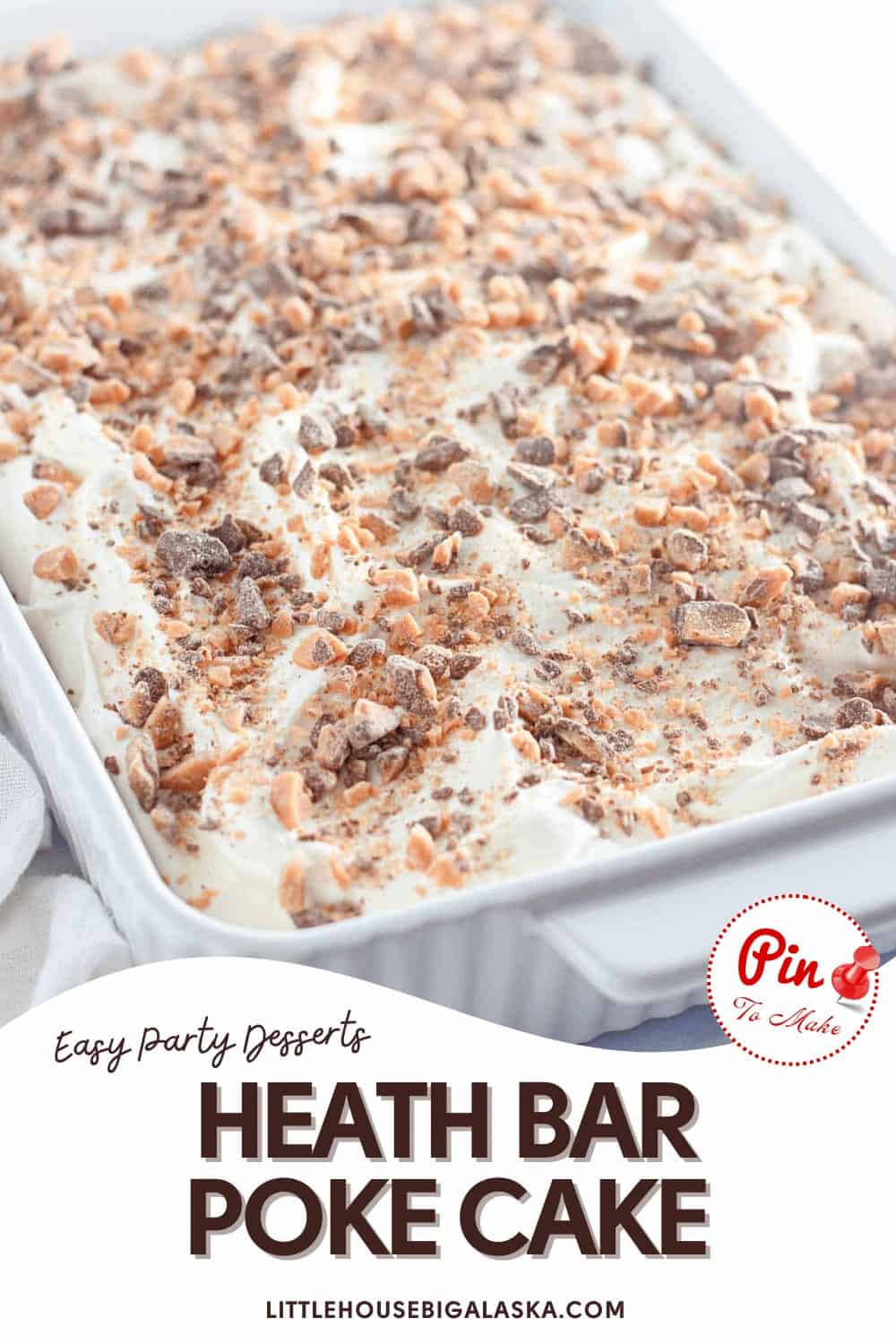 A rectangular Heath Bar Poke Cake in a white baking dish, topped with whipped cream and crushed Heath Bars, is ready to serve.
