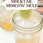 A glass mason jar filled with a light brown Mocktail Moscow mule, garnished with a lime slice, sits chilled and refreshing.