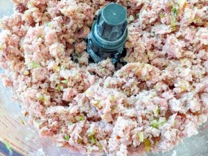 Minced ham, pickles, and other ingredients mixed in a food processor.