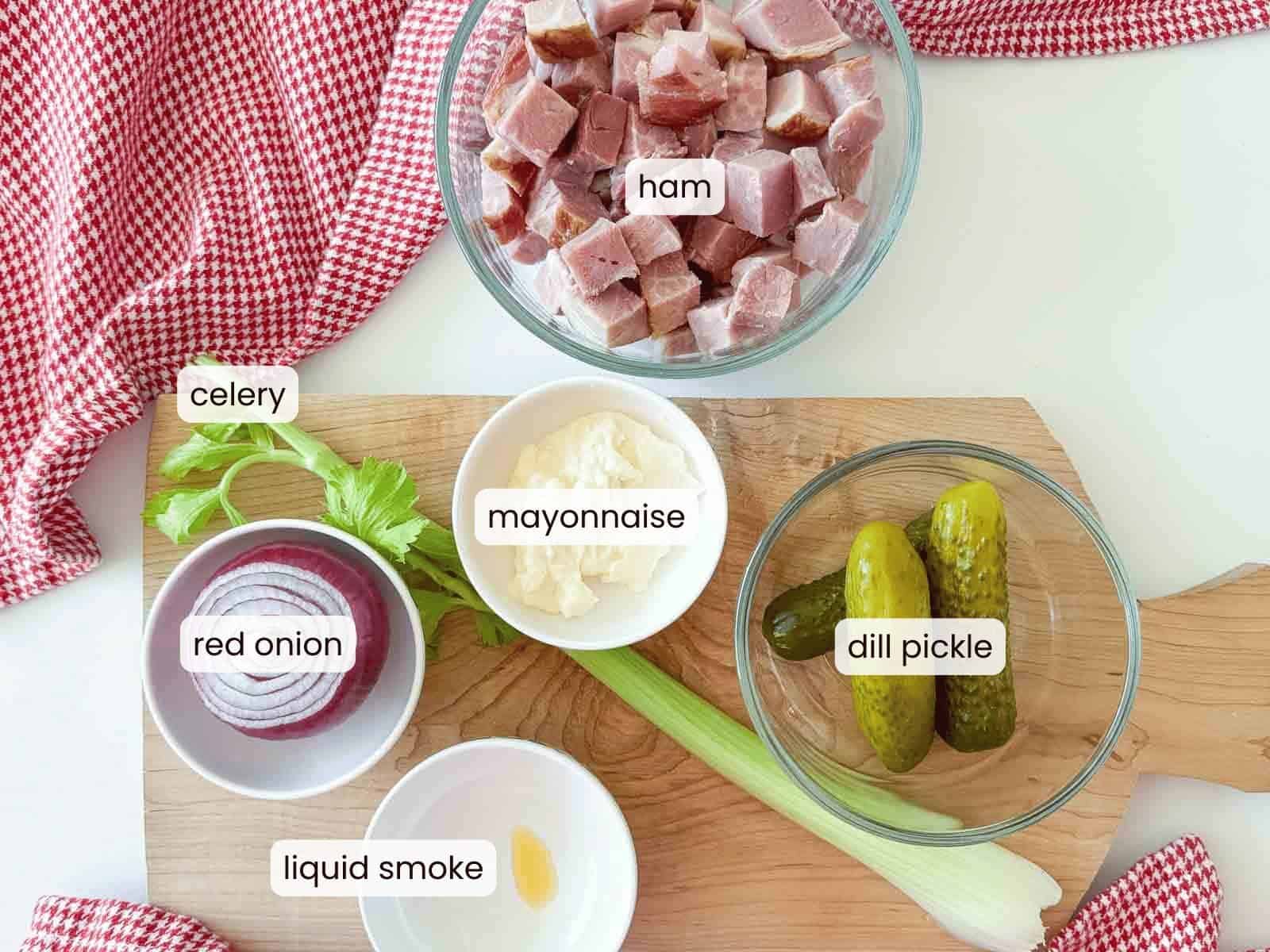 Old-Fashioned Ham Salad with chopped ham, celery, red onion, mayonnaise, dill pickles, and a hint of liquid smoke arranged on a wooden board with a red checkered cloth.