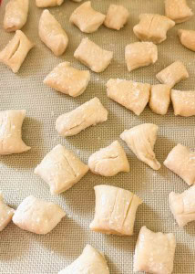 Small pieces of raw dough are spaced out on a silicone baking mat, ready for baking.