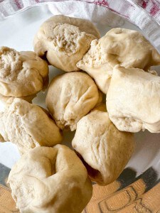 Seven pieces of raw dough are placed on a clear glass plate.