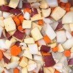 Chopped root vegetables including sweet potato, carrot, and onion, ready for cooking.