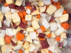 Chopped root vegetables including sweet potato, carrot, and onion, ready for cooking.