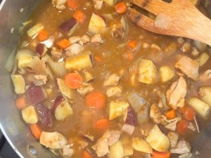 A close-up shot shows chicken curry with chunks of potato, carrot, and onion in a pot.