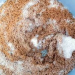 A close-up of brown sugar and white granulated sugar mixed together in a light blue bowl.