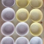 A 12-cup muffin tray lined with alternating yellow and white paper cupcake liners.