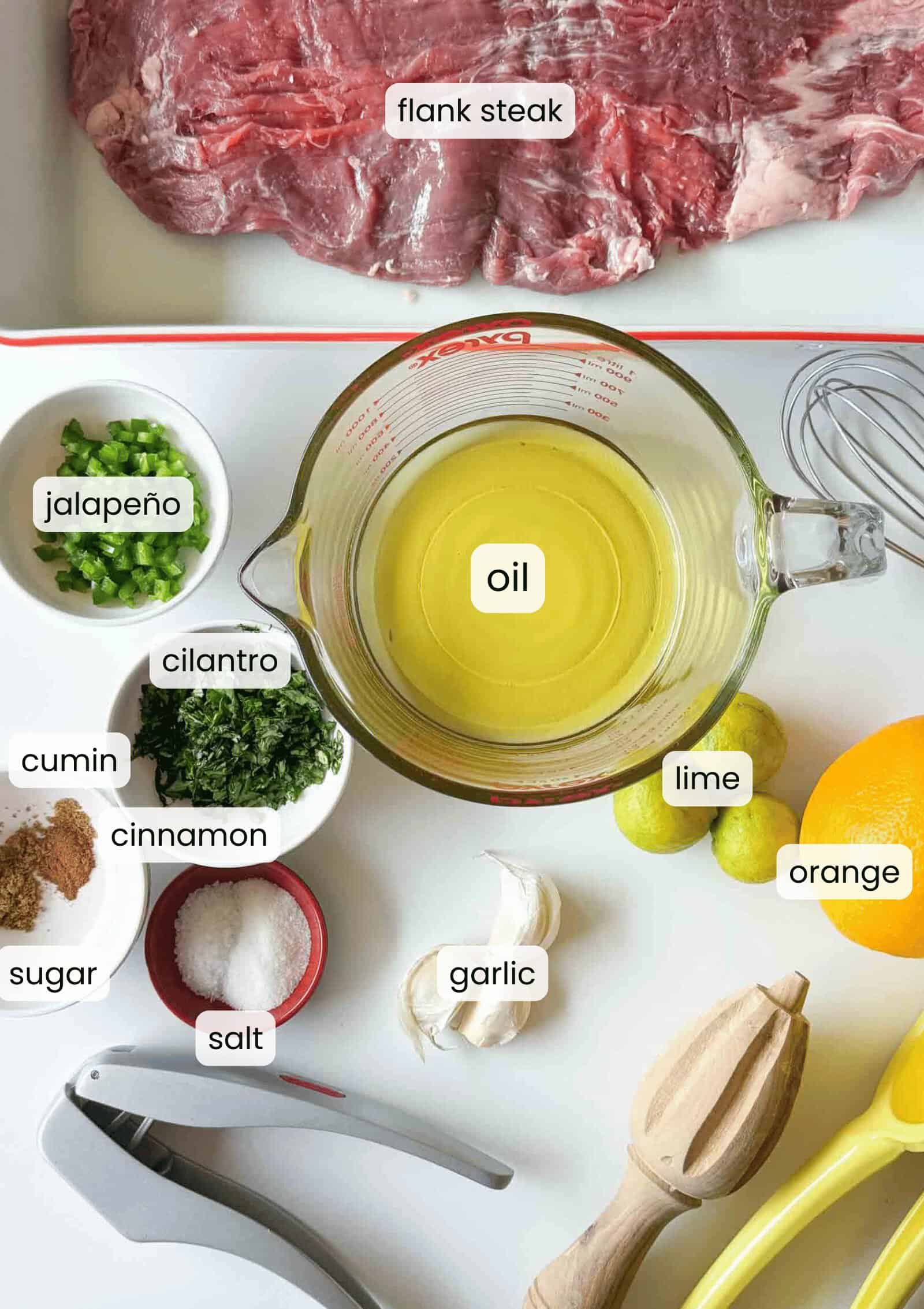 Ingredients for easy carne asada marinade are displayed, including flank steak, oil, lime, orange, garlic, salt, sugar, cilantro, cinnamon, cumin, jalape&ntilde;o&mdash;plus essential kitchen tools.