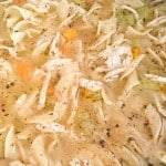 Close-up of easy chicken noodle soup with shredded chicken, egg noodles, carrots, celery, and pepper in broth.