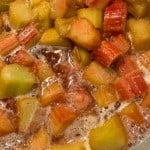 Chopped rhubarb pieces simmering in liquid, with bubbles forming around the fruit.