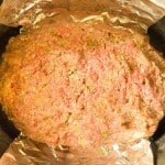 Raw meatloaf mixture shaped into a loaf on a sheet of aluminum foil, ready to be cooked.