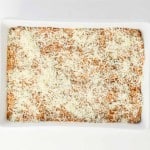 Rectangular white baking dish filled with a baked Spaghetti Squash Bake topped with shredded cheese, viewed from above on a white background.