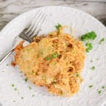A serving of Spaghetti Squash Bake with melted cheese and ground meat, garnished with parsley, on a white plate with a fork.