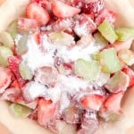 Unbaked pie crust filled with chopped strawberries and rhubarb, topped with a sprinkle of sugar&mdash;perfect for making a classic strawberry rhubarb pie.