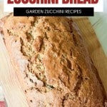 A loaf of homemade zucchini bread sits on a wooden cutting board, with bold text reading "Freshly Baked Zucchini Bread" above it.