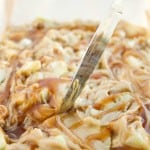 A knife swirls caramel into a creamy batter in a baking pan, creating a marbled pattern before baking.
