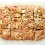 A batch of caramel apple blondies cut into twelve squares, displayed on parchment paper.