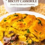 A serving of French dip biscuit casserole with roast beef and melted cheese is plated on a white dish, garnished with parsley.