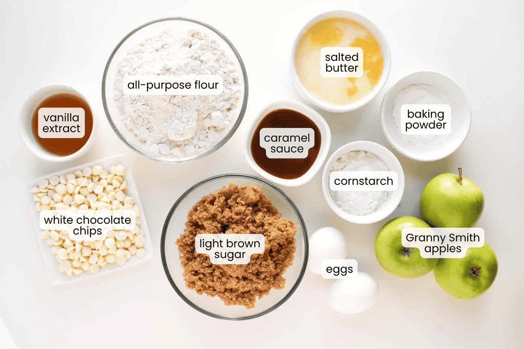 Ingredients for baking: all-purpose flour, salted butter, baking powder, vanilla extract, caramel sauce, cornstarch, white chocolate chips, light brown sugar, eggs, and Granny Smith apples.