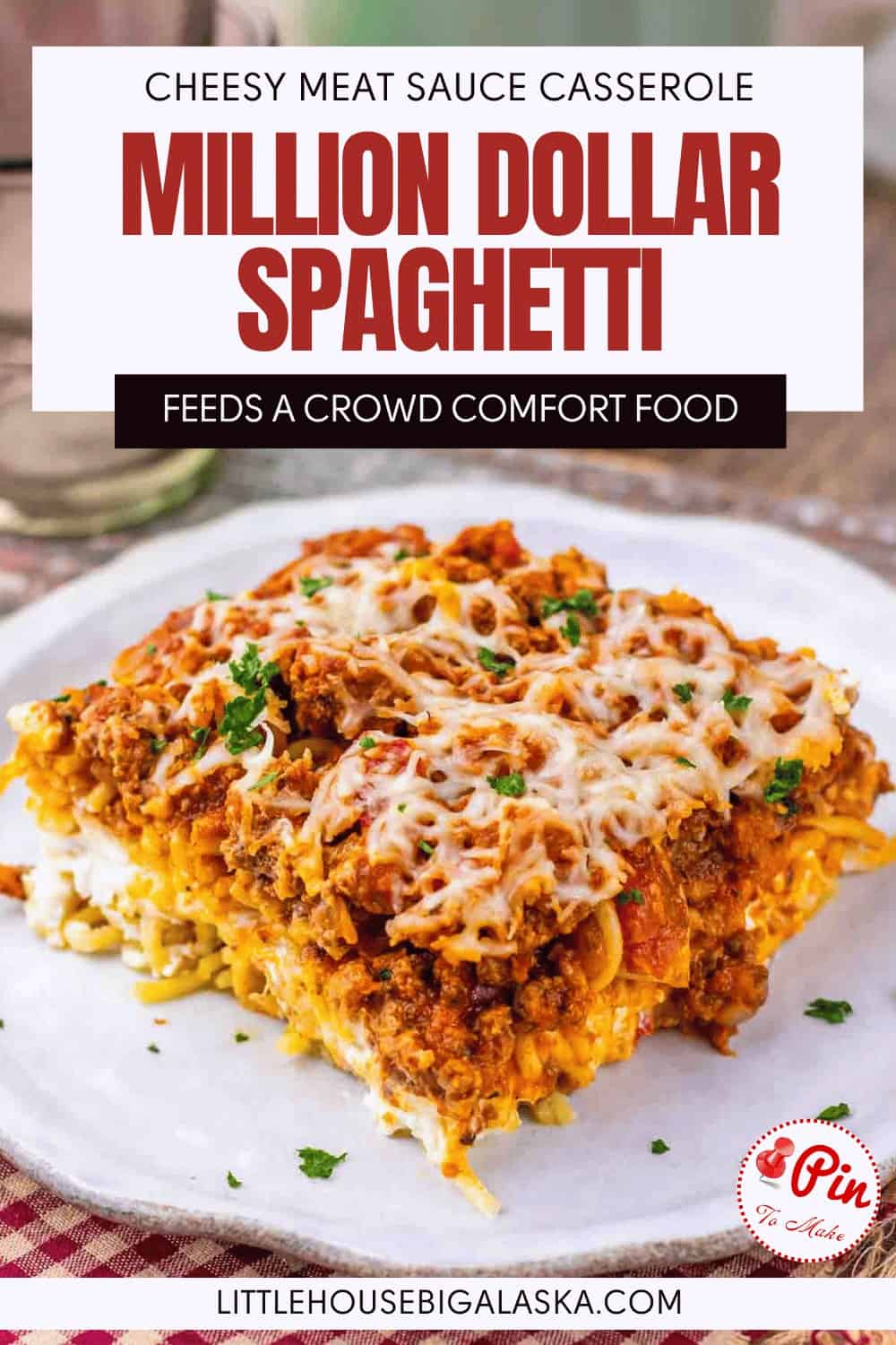 A serving of cheesy Million Dollar Spaghetti baked casserole with meat sauce on a white plate, topped with melted cheese, sits on a table with a fork.