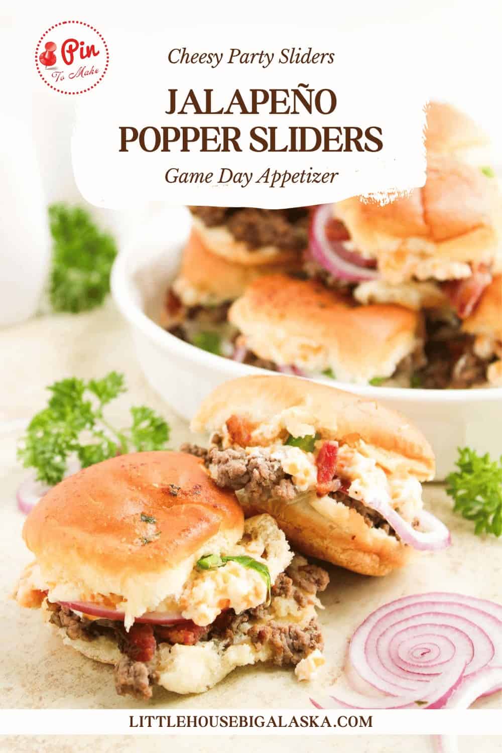 Three jalapeño popper sliders filled with beef, cheese, and toppings sit on a white surface, accompanied by sliced red onions and parsley. More jalapeño popper sliders are stacked on a plate in the background.