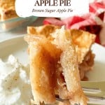 A fork holds a bite of old fashioned apple pie close to the camera, with whipped cream and more pie visible in the background. Text overlay describes the dessert as “Old Fashioned Apple Pie.”.