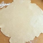 Rolled out pie dough on a floured wooden surface, ready to be shaped or filled for an old fashioned apple pie.