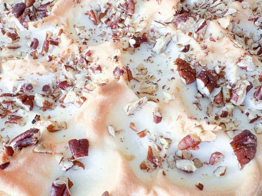 Close-up of a toasted meringue topping sprinkled with chopped pecans.