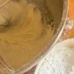 A stand mixer bowl containing Iced Gems batter, with a nearby bowl of powdered sugar.