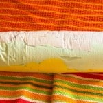 A cylindrical roll of paper towel sitting on fabric striped like iced gems.