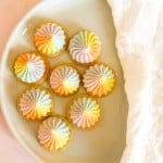 Eight Iced Gems topped with swirls of pastel-colored frosting on a white plate.