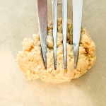 A metal fork pressed into a ball of cookie dough.